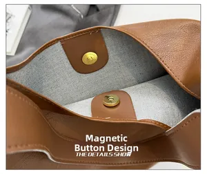 Detail of the magnetic closure on a brown pebble leather tote bag with fabric lining