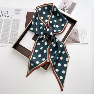 Detail of dark green polka dot silk scarf tied in a bow inside a premium gift box