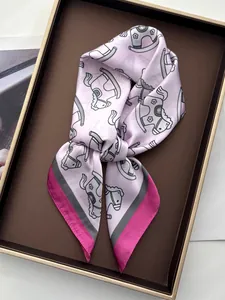 Close-up of pink silk scarf with rocking horse print in a luxury gift box