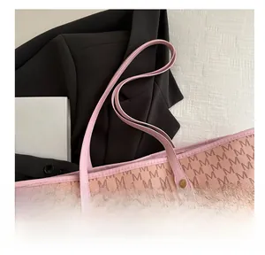 Detail view of pink monogram tote bag with slim handles and vintage rivets