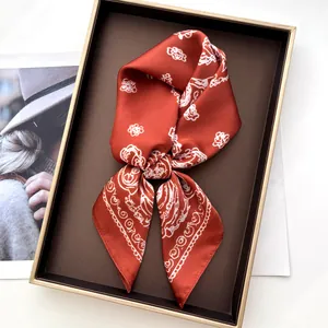 Close-up of elegant red floral silk scarf presented in a luxury gift box with golden frame