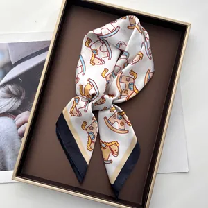 Close-up of elegant silk-like square scarf with playful rocking horse print pattern