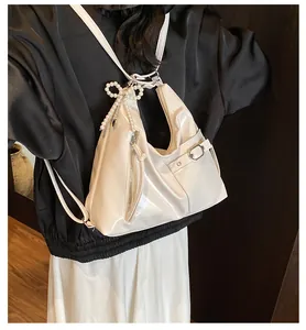 Detailed shot of white glossy faux leather bag with pearl bow charm and silver hardware