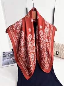 Detailed view of large orange satin scarf with white paisley patterns draped on a dress