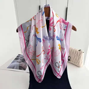 Detailaufnahme eines Seidenschals mit bunten Schleifen-Prints und rosa Kontrastrand