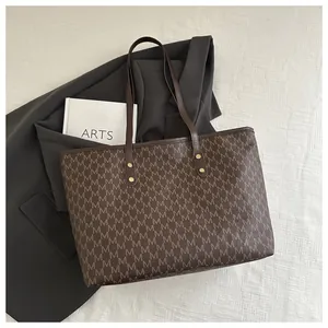 Close-up of vintage brown tote bag with M-pattern print and leather shoulder strap