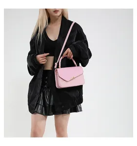 Detail of pink fashion handbag with gold clasp and textured flap shown on a model
