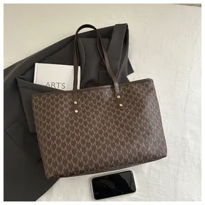 Detail of vintage brown tote bag with M-pattern print and gold rivet hardware accents