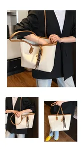 Detalle del bolso tote de cuero con amuleto de pañuelo de seda y bordes contrastados