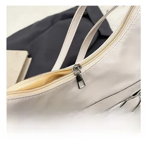 Detailed close-up of cream PU leather shoulder bag with silver zipper and metal buckle