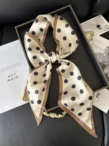 Polka dot silk scarf with champagne base and dark brown border tied as a stylish bow
