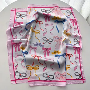 Detailansicht eines eleganten Seidenschals mit bunten Schleifenmustern und rosa Rand