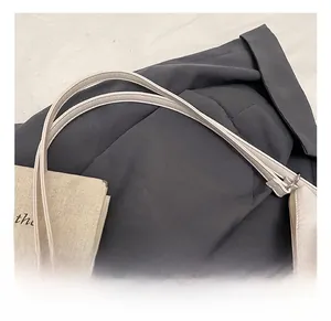 Detail of comfortable faux leather handle and elegant pearl chain on beige shoulder bag