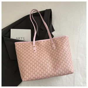 Detail of pink monogram tote bag with gold rivets on white textured background