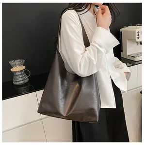 Detail of deep brown PU leather tote bag showing wide strap and smooth textured finish