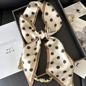 Detail of cream silk scarf with black polka dots and brown border on luxury tray