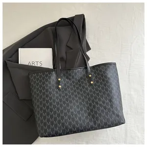 Detail of vintage pattern tote bag with M print, leather texture and gold hardware