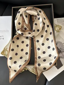 Detailed view of polka dot silk scarf draped on a black tray with vintage accessories