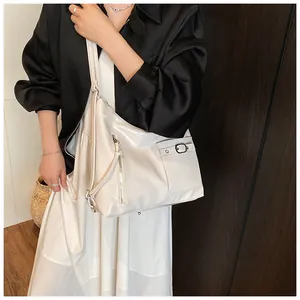 Detailed side view of white glossy leather tote bag with metallic buckle and zipper