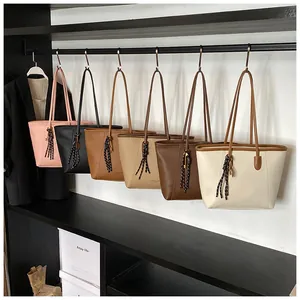 Fila de bolsos tote minimalistas en seis colores colgados con adornos trenzados