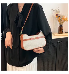 Borsa a spalla marrone e crema con fiocco, indossata da una modella in un interno