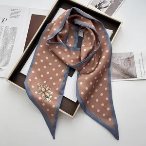Nahaufnahme eines Retro-Seidenschals mit Punkten und Blumen auf goldenem Tablett