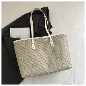 Macro detail of monogram M print tote bag with metallic studs and faux leather handles