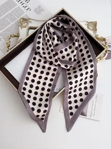 Detailed view of pink polka dot silk scarf draped elegantly in a gold metal tray