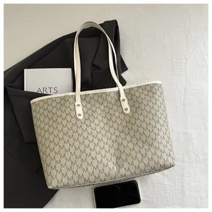 Macro shot of M monogram pattern and white shoulder strap with gold hardware on tote bag