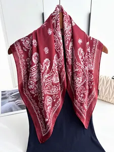 Close-up of a deep red paisley pattern silk-like square scarf on a wooden hanger