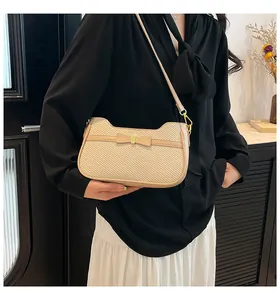 Dettaglio di borsa a spalla in tessuto beige con fiocco a contrasto e fibbia in metallo