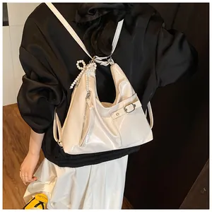 White glossy patent leather backpack detail with pearl bow charm and decorative metal buckle