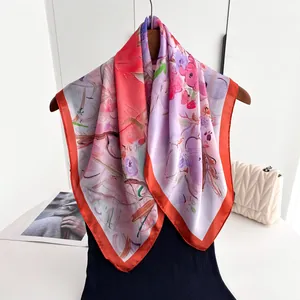 Détail d'un foulard carré soyeux avec imprimé floral à l'huile et bords roulés rouges