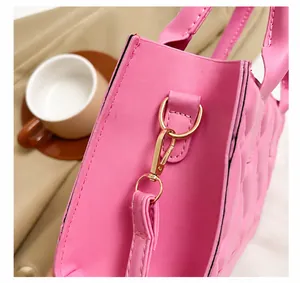 Detail van lichtgouden hardware en springhaken op de roze gewatteerde kunstleren tas
