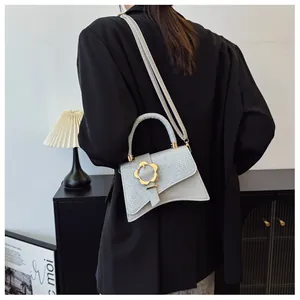 Détail du sac à bandoulière argenté avec boucle fleur dorée et textures en patchwork moderne
