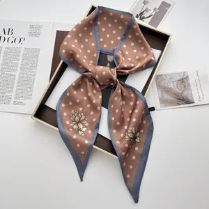 Detailansicht eines Seidenschals mit Punkten und Blumenprint in einer Geschenkbox