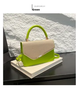 Detail of green linen textured handbag with gold hardware and woven flap on books