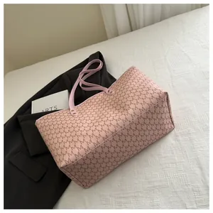 Detail of pink tote bag showing repeated M letter print and reinforced metal rivets