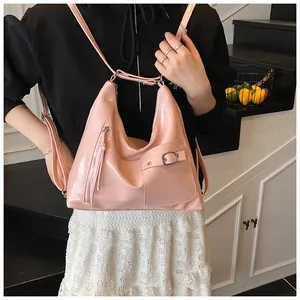 Pink patent leather shoulder bag detail with tassels and buckle pocket on model