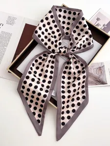 Detailed view of champagne pink polka dot silk scarf tied in a bow on a black tray