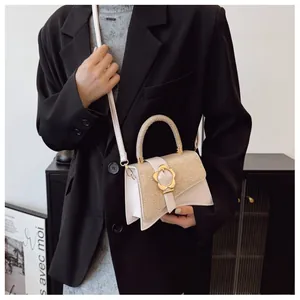 Détail d'un sac bandoulière élégant avec boucle fleur dorée et finitions contrastées