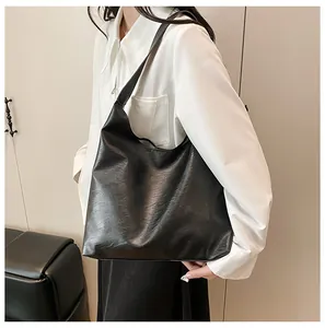 Close-up of black leather tote bag showing glossy texture and wide shoulder strap
