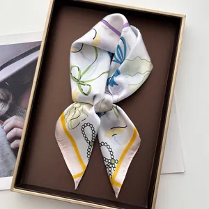 Nahaufnahme von Seidenschal mit Schleife und Blumendruck in einer hochwertigen Geschenkbox