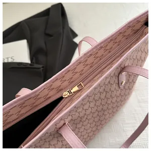 Close-up of pink monogram tote bag featuring a gold zipper and smooth faux leather texture