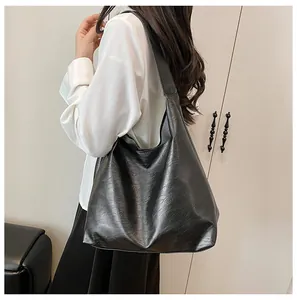 Detail of a large black leather hobo bag showing litchi texture and drape on a shoulder