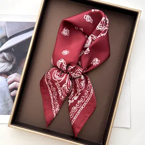 Detail of burgundy silk scarf with floral print neatly folded in a decorative tray