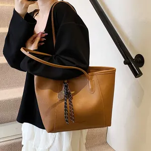 Bolso tote de cuero marrón de gran capacidad con un moderno colgante de raqueta de tenis