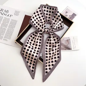 Close-up of beige polka dot satin scarf tied in a bow on a stylish decorative tray