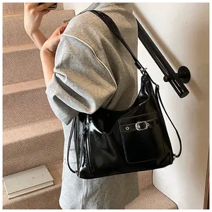 Detailed close-up of glossy black leather handbag texture and metal buckle on the shoulder bag