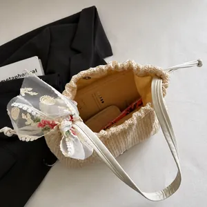Detail of straw beach tote featuring lace bow, leather straps and spacious interior